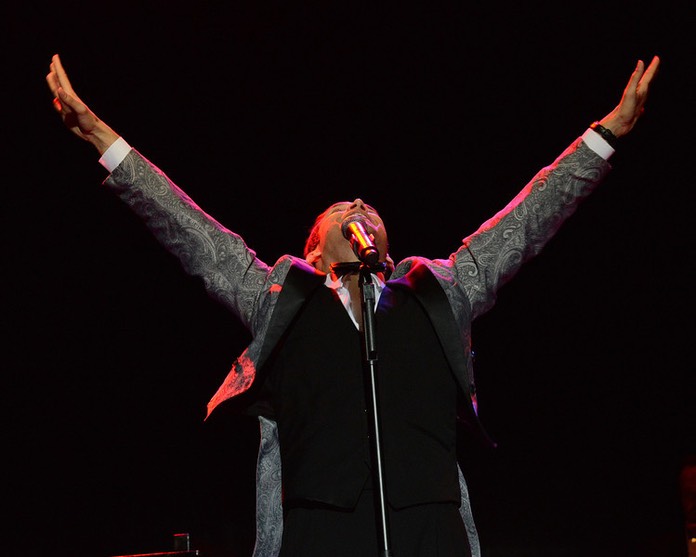 Scotty at mic stand with arms in the air